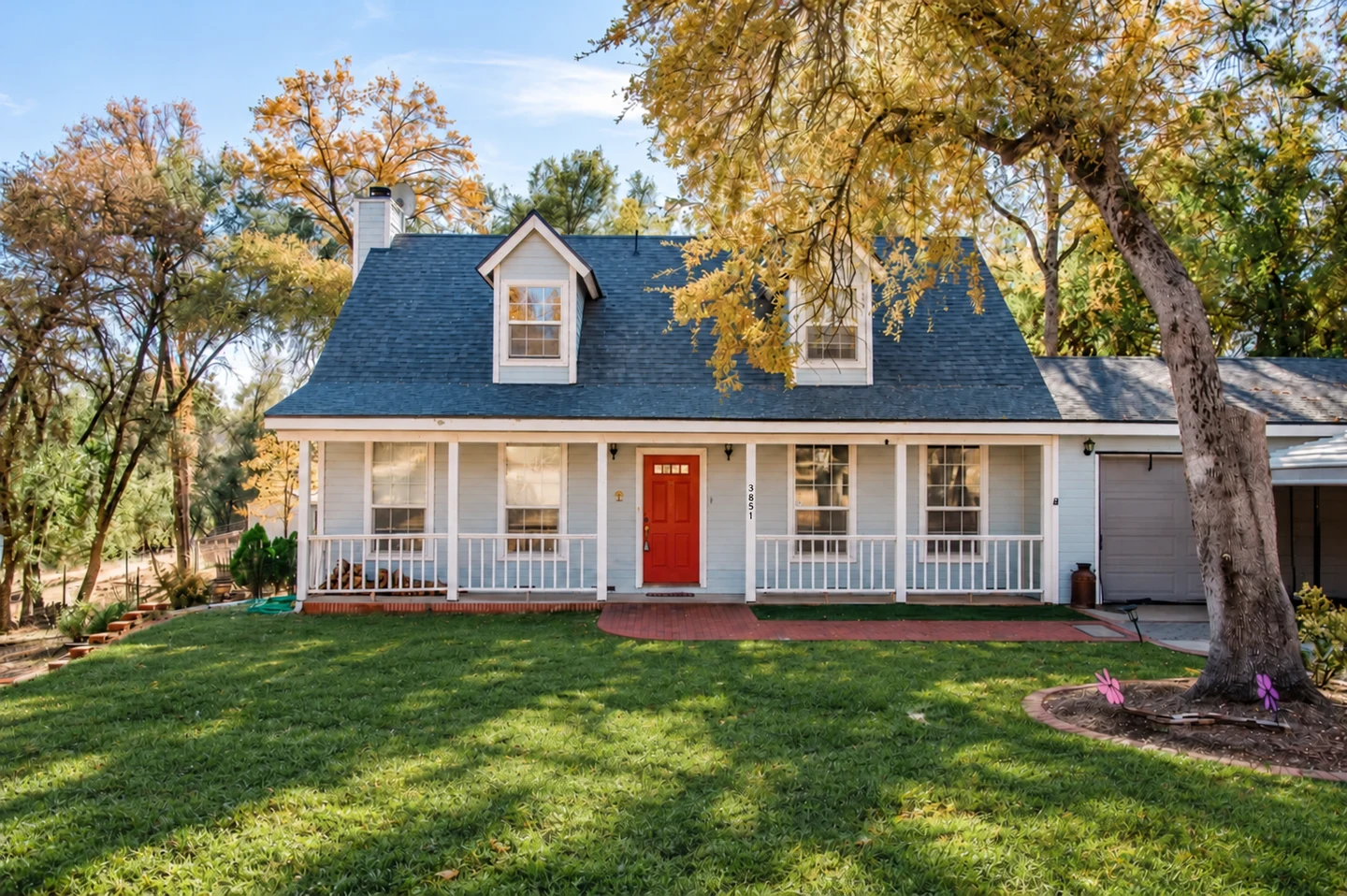 A TRADE residential home with a porch and surrounding trees.